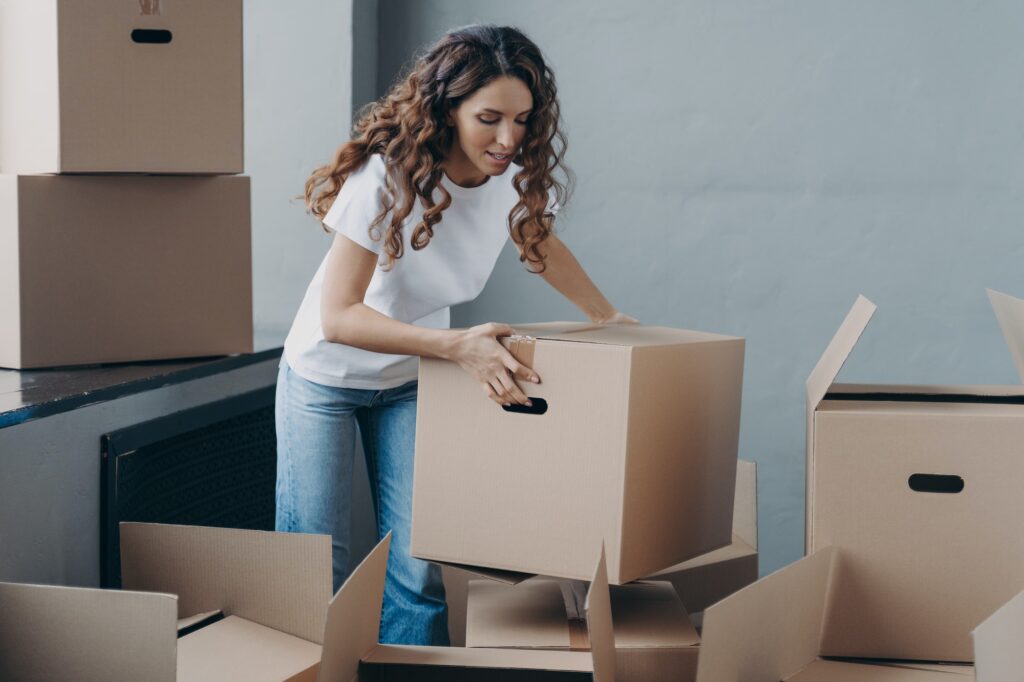 Eine Mieterin packt ihre Sachen in Kisten, um aus der Mietwohnung auszuziehen. Umziehen, rental dwelling